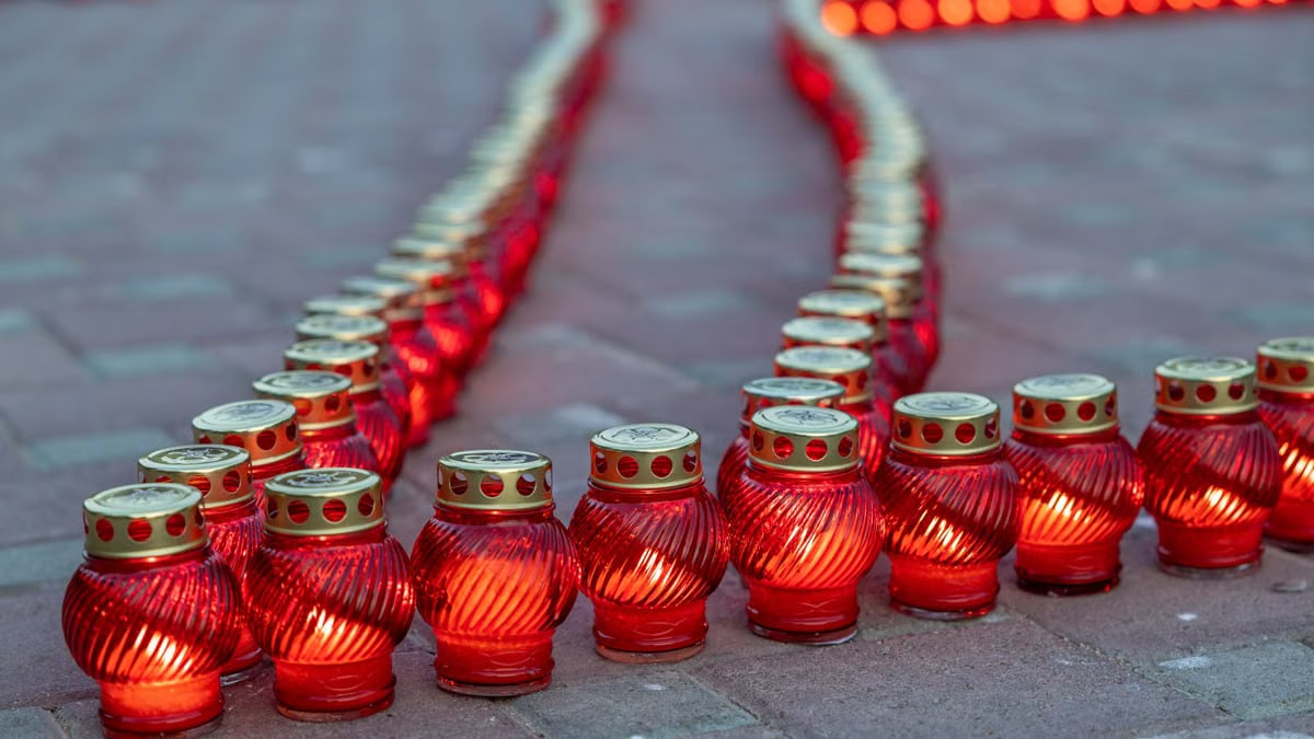 Rows of glowing red candles arranged on a paved surface, creating a warm ambiance.